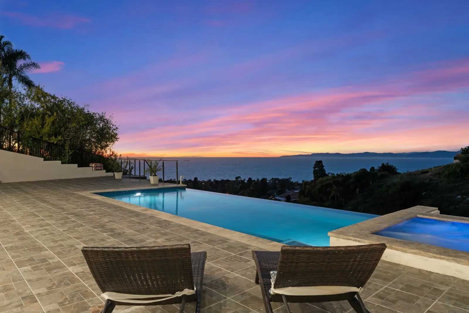 Infinity pool and spa at sunset overlooking the Pacific Ocean