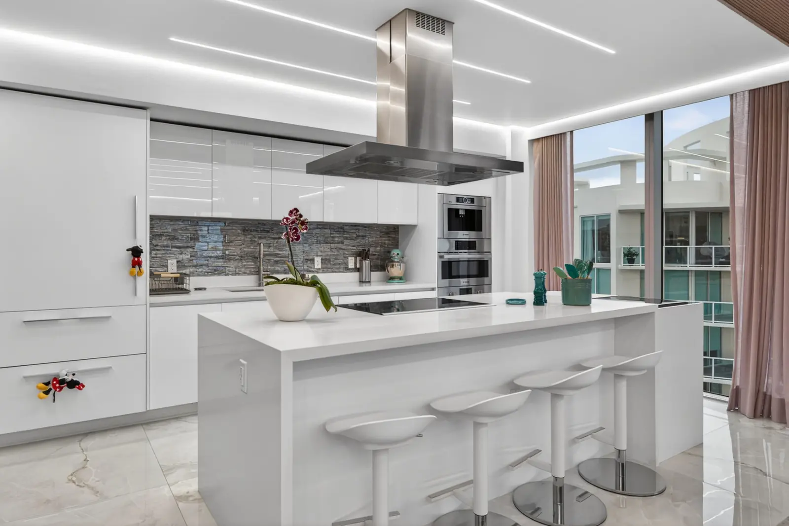 White kitchen with a waterfall island, stainless hood and barstools